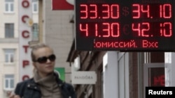 A woman passes by a sign displaying currency exchange rates in Moscow on June 1.