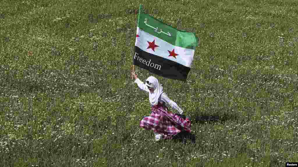 A Syrian refugee runs with an opposition flag during a demonstration against Syrian President Bashar al-Assad outside the Syrian Embassy in Amman, Jordan, on April 13. (Reuters/Ali Jarekji)