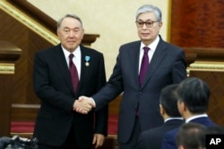 Kazakh President Qasym-Zhomart Toqaev and former Kazakh President Nursultan Nazarbaev shake hands after Toqaev's inauguration ceremony in Astana in 2019.