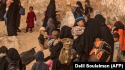Женщины, которые, как утверждается, являются членами семей боевиков экстремистской группировки «Исламское государство» (ИГ), с детьми на выходе из деревни Багуз в сирийской провинции Дейр-эз-Зор. 14 марта 2019 года.