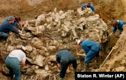 International war crimes investigators clear away soil and debris from dozens of Srebrenica victims buried in a mass grave near the village of Pilica, northeast of Tuzla, in September 1996.