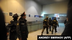 Police officers look (L) at Russian Federal Security Service (FSB) agents (R) rushing inside Moscow's Domodedovo international airport on January 24, 2011, shortly after an explosion.