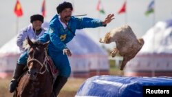 Игрок сборной Казахстана забрасывает тушу козла в тай-казан на первом Чемпионате Азии по кокпару в Астане. 12 сентября 2013 года.
