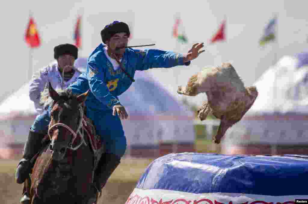 A rider from the Kazkah team drops the headless goat into the container for a score against Russia during the first Asian kokpar championship.