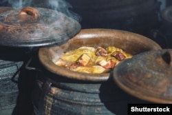 A traditional Serbian dish of cabbage and pork being stewed in a clay pot.