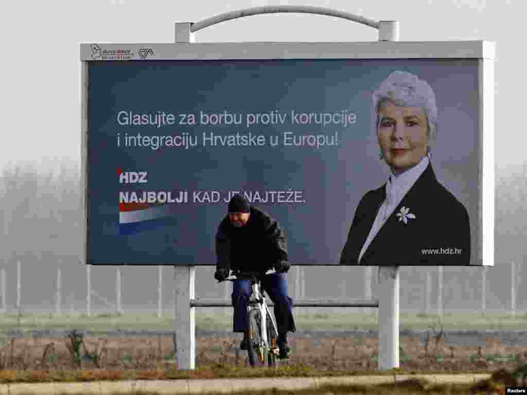 A man rides past a billboard for Croatia's ruling HDZ party, led by Prime Minister Jadranka Kosor, near Zagreb airport on November 28. (REUTERS/Nikola Solic)