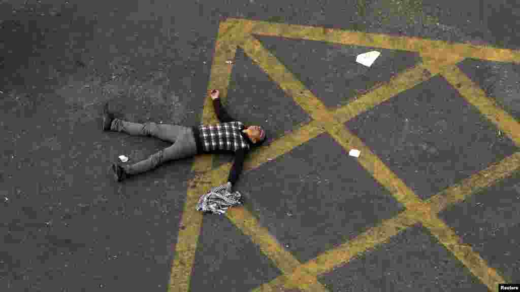 A protester lies in the street after passing out due to tear gas fired by riot police in Cairo. Police fired tear gas in a street leading to Cairo&#39;s Tahrir Square, where thousands demanded that President Muhammad Morsi quit. There were violent protests in Alexandria, Port Said, and Suez. (Reuters/Mohamed Abd El Ghany)