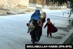 An Afghan woman flees the area after an attack on the headquarters of Save the Children in Jalalabad on January 24.