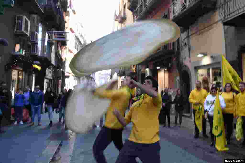In Naples, members of the Pizzaioli Acrobats Coldiretti celebrate a decision by UNESCO to make the art of Neapolitan "Pizzaiuolo" an "intangible heritage." The art of the Neapolitan "Pizzaiuolo" is a culinary practice consisting of four different phases relating to the preparation of the dough and its baking in a wood-fired oven. The practice originates in Naples, where around 3,000 Pizzaiuoli now live and perform. (AFP/Tiziana Fabi)