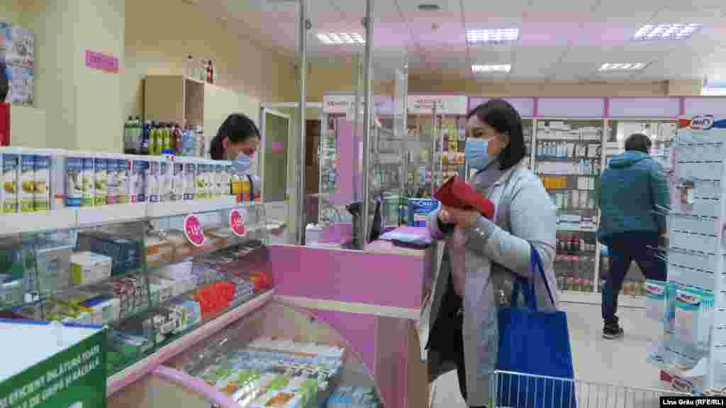 Farmaciile nu duc lipsă de clienți, deși fluxul acestora a scăzut față de zilele trecute. În interior intră doar câteva persoane, rândul e afară, cu respectarea distanței de un metru. 