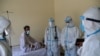FILE: Healthcare workers treat a person infected with the coronavirus in the eastern Afghan province of Laghman in June.