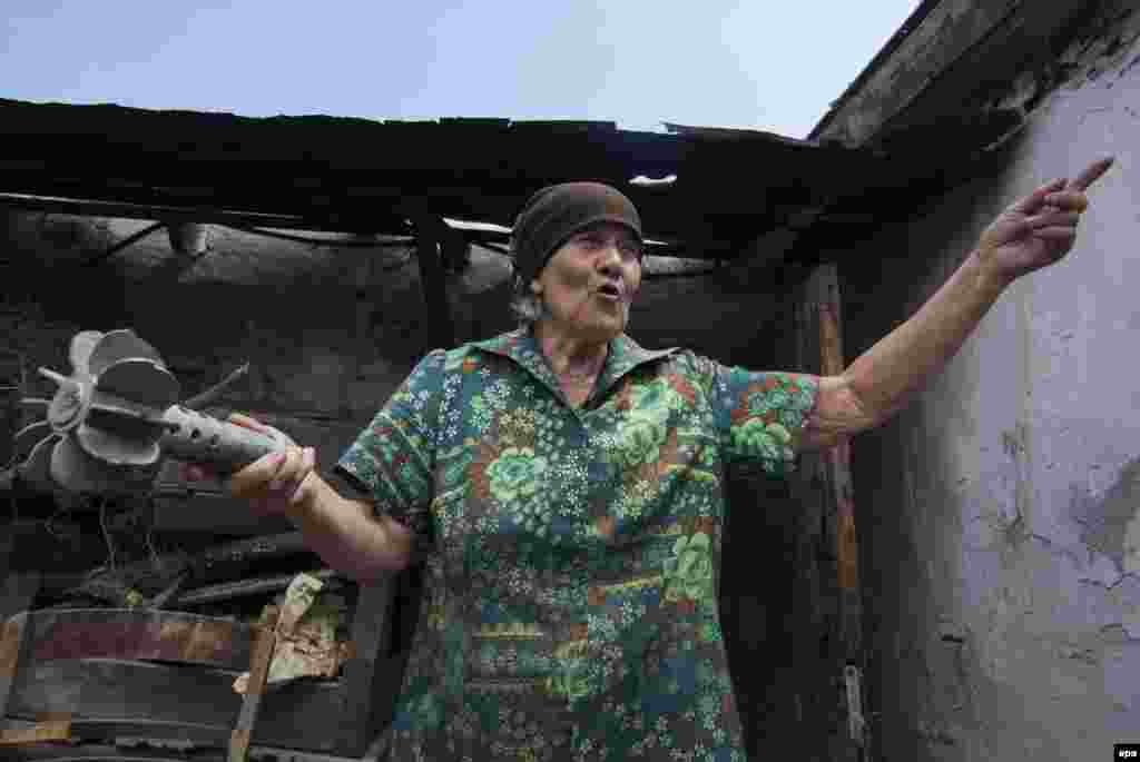 Tamara Kutnenko, 71, shows a part of a spent mortar shell next to her damaged house after recent shelling on territory controlled by the Ukrainian Army in the village of Novotroitskoe in the Donetsk region. (epa/Sergei Vaganov)