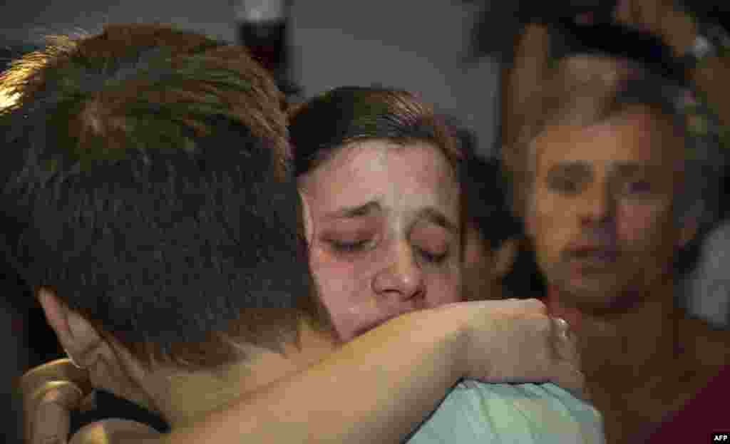 Argentinian Greenpeace activist Camila Speziale (center) hugs a relative as her father, Nestor (right), looks on after her arrival in Buenos Aires on December 28 following 100 days in detention in Russia. (AFP/Alejandro Pagni)