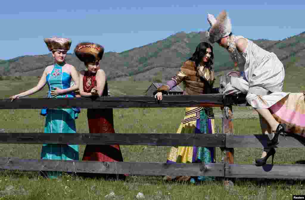 Models of the Altyr fashion theater, dressed in Khakas national costumes, climb over a wooden fence during a photo session, as part of the rehearsal for the Tun-Pairam traditional holiday (The Holiday of the First Milk) celebration at a museum preserve outside the village of Kazanovka near Abakan in the Republic of Khakassia, Russia. (Reuters/Ilya Naymushin&nbsp;)