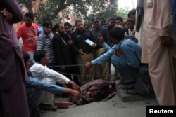 Таспен ұрып өлтірілген Фарзананың денесінің жанында айғақ жинап жүрген полицейлер. Пәкістан, Лахор, 27 мамыр 2014 жыл.