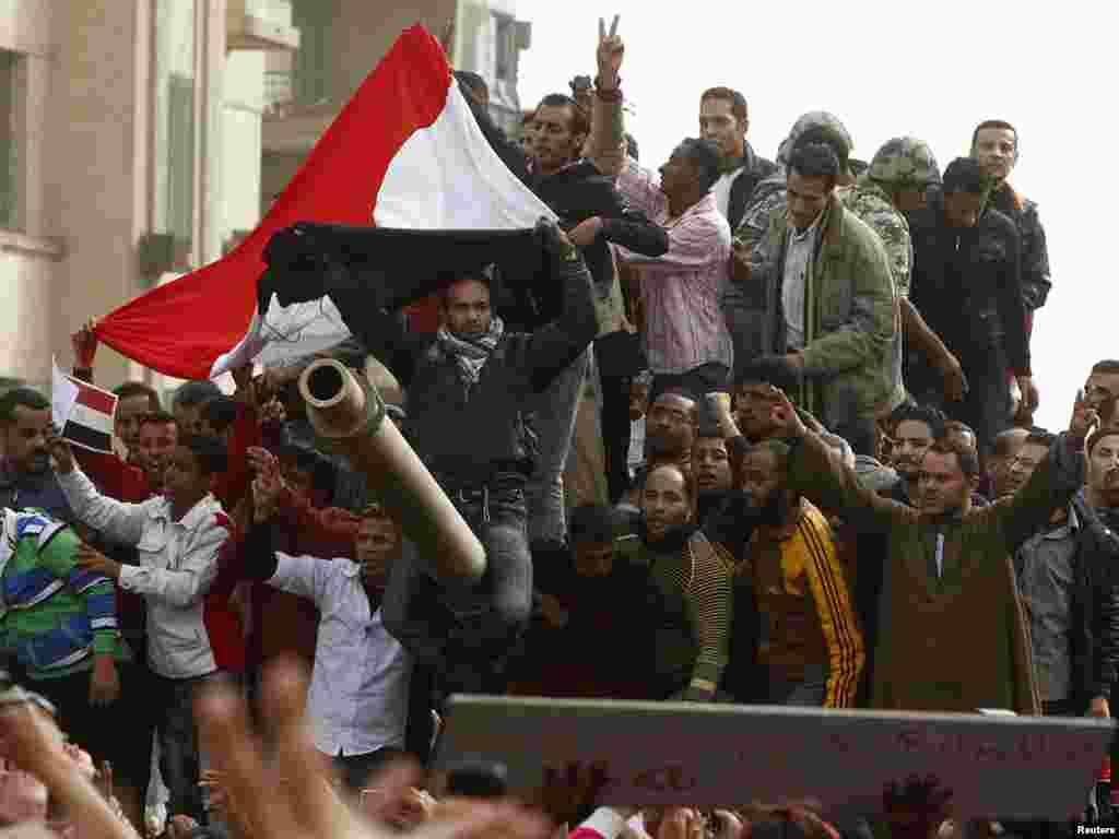 Demonstrators celebrate atop an army tank in Tahrir Square during protests in Cairo on January 29.