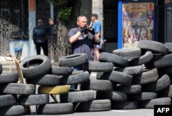 Un militant pro-rus păzește o baricadă în Donețk.