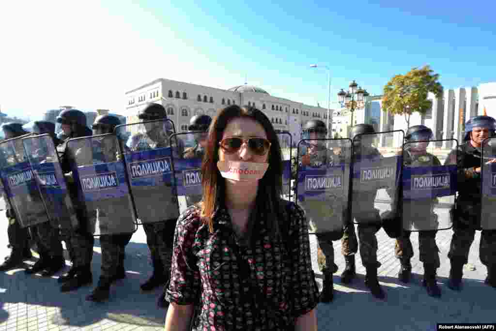 A woman with a sticker on her mouth that says "Freedom" stands in front a police cordon during a protest in the Macedonian capital, Skopje. Journalists were gathering to protest a more than four-year sentence against a colleague for revealing the identity of a murder witness in a case that has international organizations concerned over press freedoms in the country. (AFP/ Robert Atanasovski)
