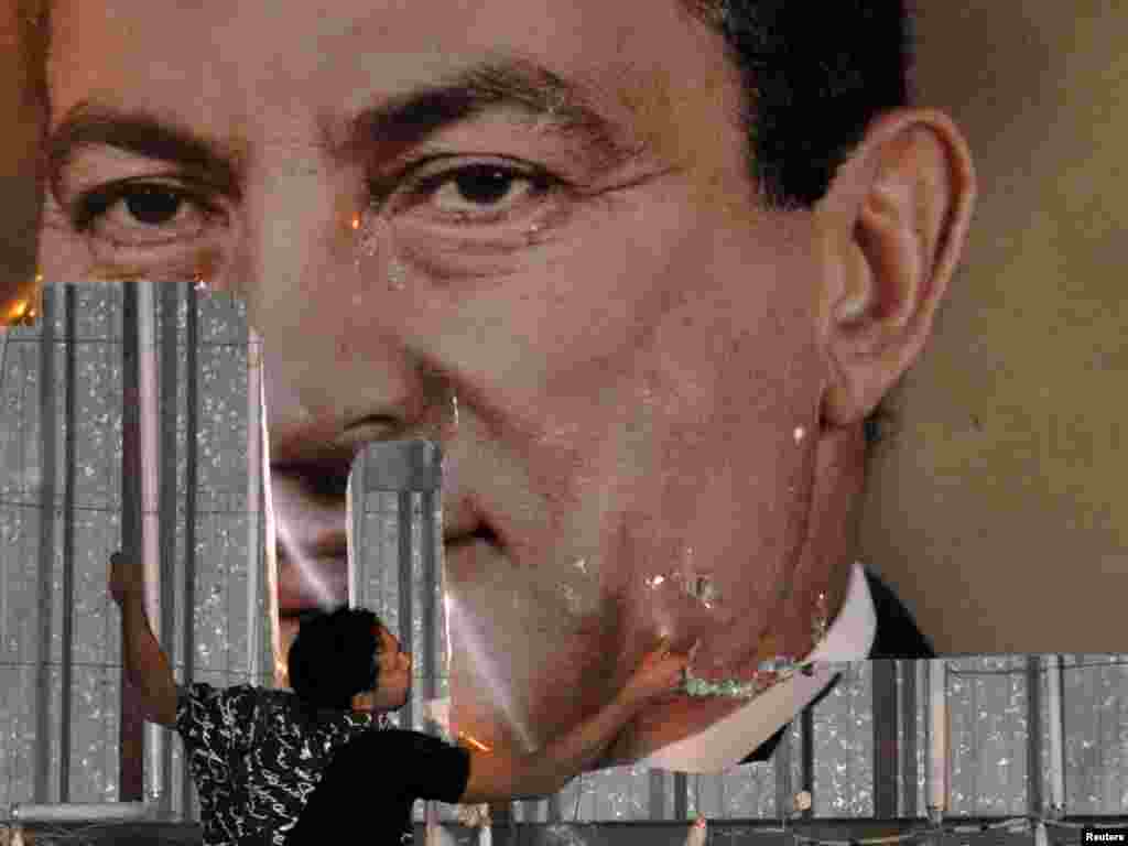 An antigovernment protester defaces a picture of President Hosni Mubarak in Alexandria