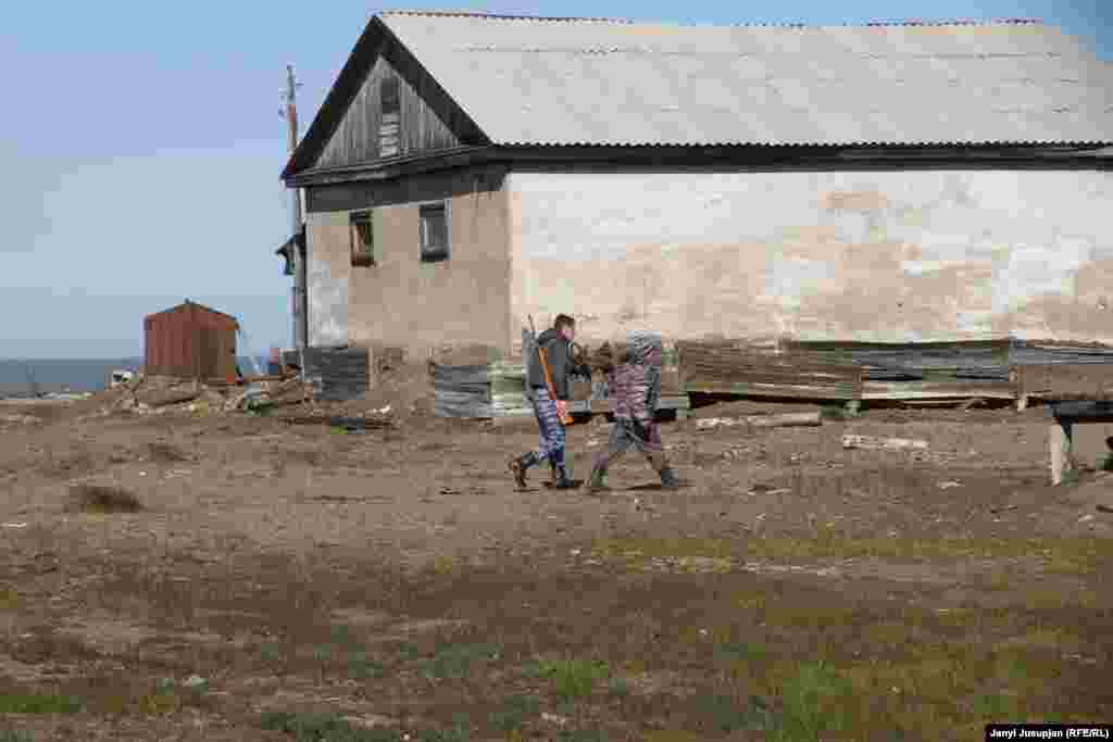 The man with the gun is the local policeman, responding to a sighting of a polar bear. If he finds it, he must shoot in the air to scare it away.