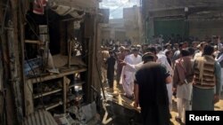 Residents gather near a damaged shop in a market after a blast in Parachinar, the capital of the Kurram tribal district on March 31.