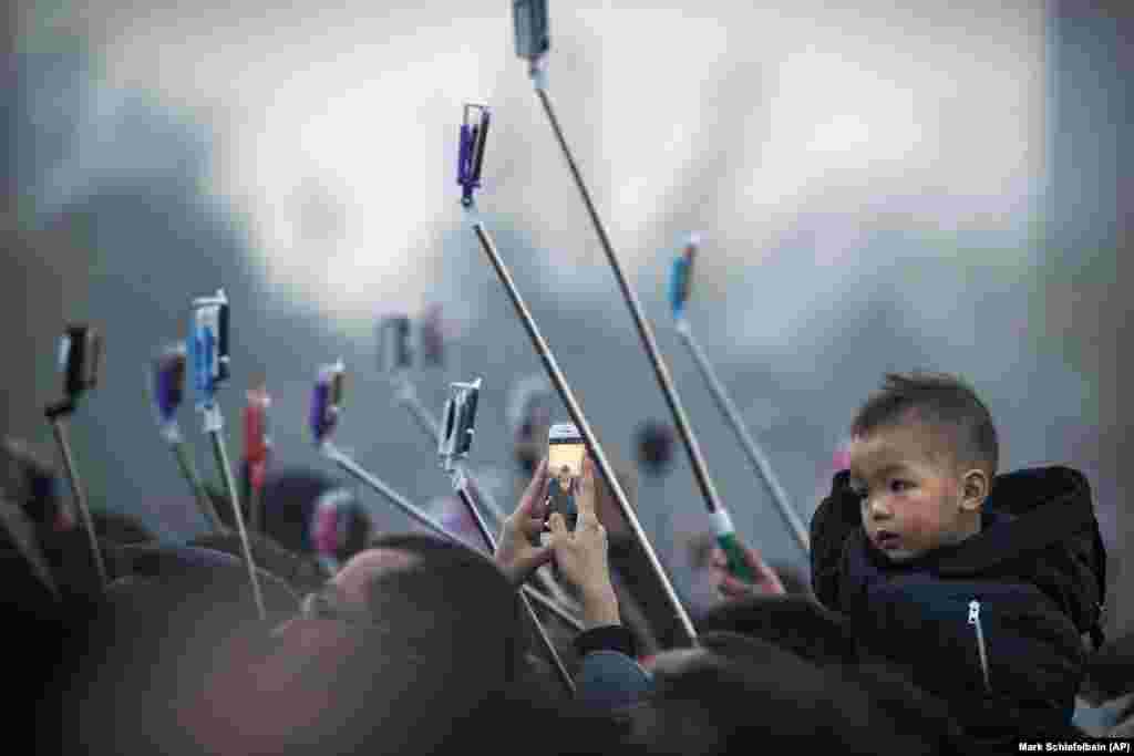 Tourists take photos of the daily flag-raising ceremony in Tiananmen Square on the eve of the opening session of China&#39;s National People&#39;s Congress (NPC) in Beijing. (AP/Mark Schiefelbein)