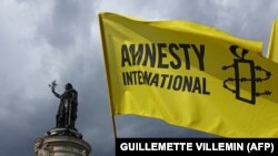 Флаг Amnesty International на демонстрации в Париже. 