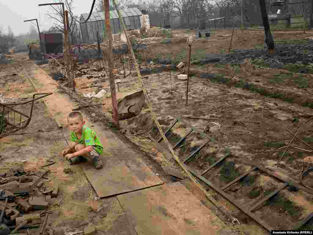 Lyosha barely cried when his family fled from the fire, says his mother. The photo shows the remains of their house in Borkovka.