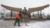 A worker removes snow in front of a statue of President Nursultan Nazarbaev at the Park of the First President on the eve of the Day of the First President in Almaty.