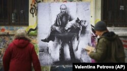 Люди проходять повз мурал болгарського художника Станіслава Бєловського, на якому президент Росії Володимир Путін тримає своє тіло, під час масштабного вторгнення Росії в Україну. Софія, Болгарія, 28 березня 2022 року