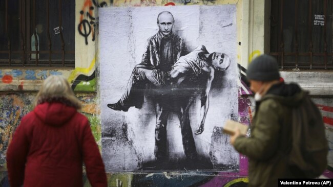 Люди проходят мимо мурала болгарского художника Станислава Беловского, на котором президент России Владимир Путин держит свое тело, во время масштабного вторжения России в Украину. София, Болгария, 28 марта 2022 года