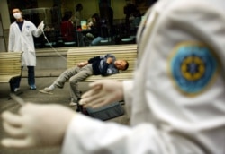 Paramedics tend to a man suspected of suffering from severe acute respiratory syndrome (SARS) after he collapses in Wuhan, China.