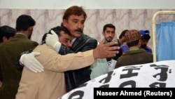 A paramedic staffer comforts a relative after a police officer and three of his family members were shot dead in Quetta.