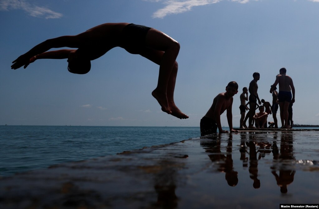A boy jumps into the Black Sea from a pier in central Sochi, Russia, on June 30. (Reuters/Dmitry Serebryakov)