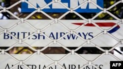 A picture taken on August 24, 2018 shows the logos of air line companies (top to bottom) Dutch KLM, British Airways, and Austrian Airlines, on the shuttered window of the closed offices of a travel agency in the Iranian capital Tehran. Air France and Brit