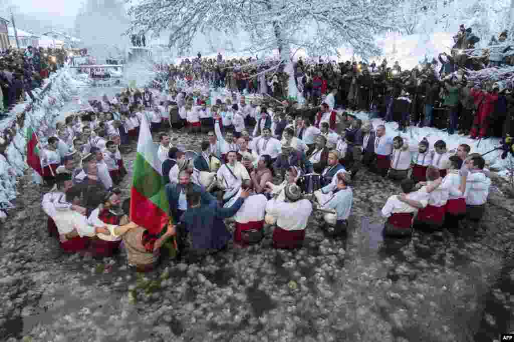 Däp boýunça, doňan Tunja derýasynda tans edýän erkekler. Bolgariýa, Kalofer şäheri. &nbsp;(AFP/Nikolay Doychinov)