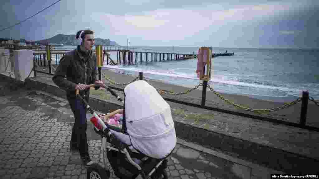 Мужчина с коляской прогуливается по набережной Судака