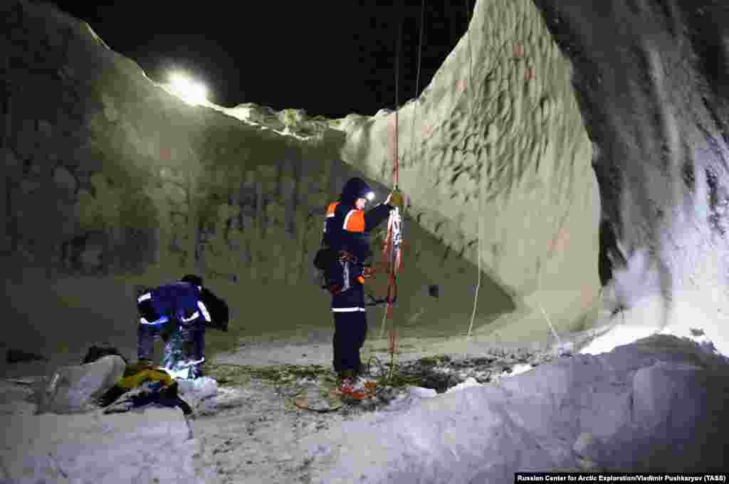 Scientists stand on the frozen lake at the bottom of the crater.