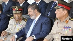 Egyptian President Muhammad Morsi (center) speaks with Hussein Tantawi (left) and Sami Anan during a ceremony in Cairo on July 17.