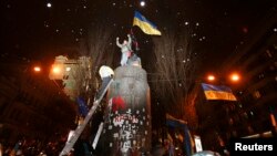 People climb atop the pedestal where a statue of Soviet state founder Vladimir Lenin was toppled earlier on December 8 after a rally organized by supporters of EU integration in Kyiv.