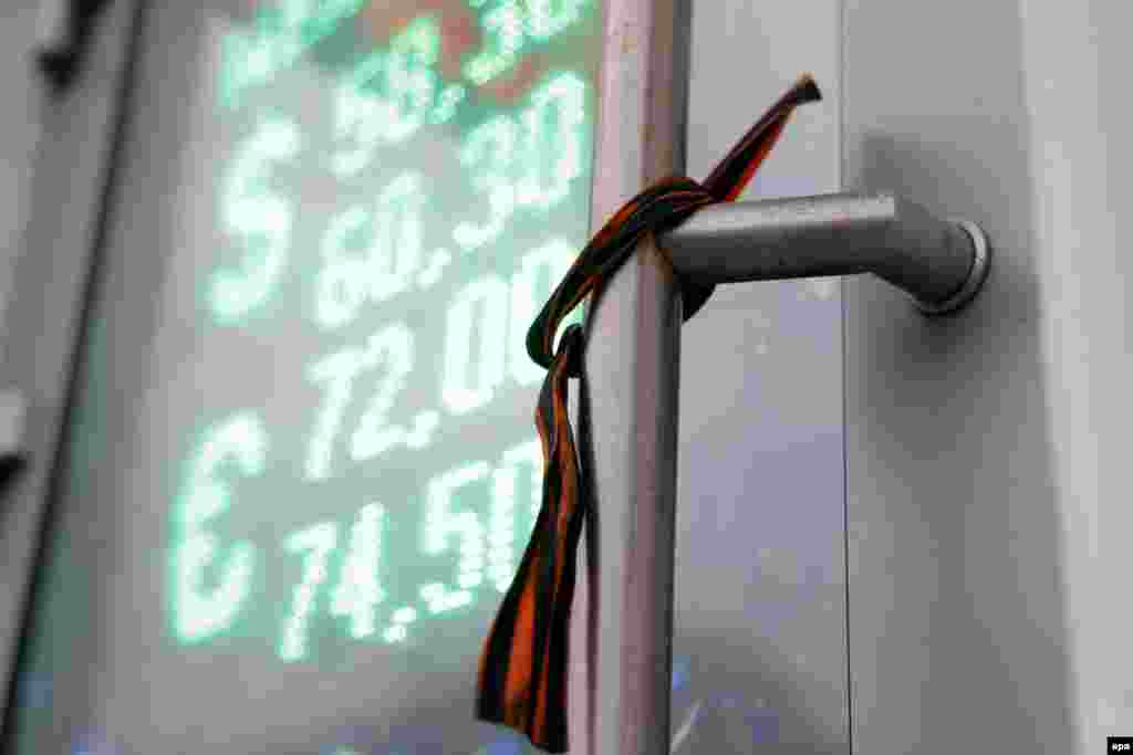 A St. George ribbon, a symbol of victory in WWII and a symbol widely associated with pro-Russian rebels in Ukraine, on an electronic information panel displaying currency exchange rates in Moscow on December 15, when the Russian currency tumbled around 10 percent. (EPA/Maxim Shipenkov)