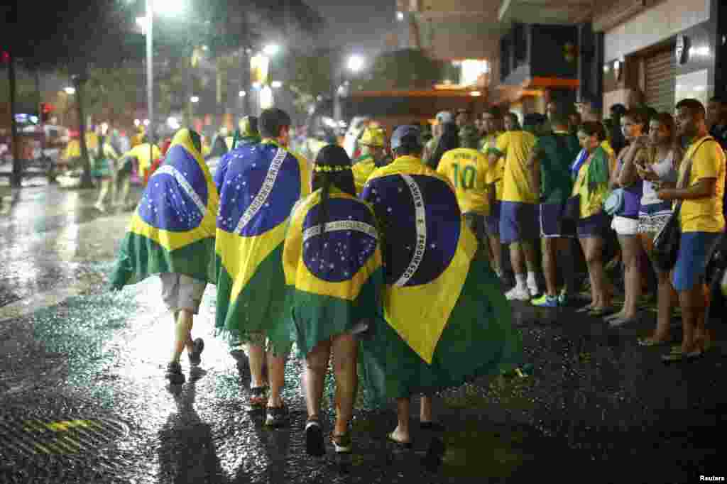 Brazil - Brazil soccer fans walk in the rain after watching a broadcast of their team's loss against Germany in their 2014 World Cup semi-final match, in Rio de Janeiro July 8, 2014. REUTERS/Jorge Silva (BRAZIL - Tags: SOCCER SPORT WORLD CUP)