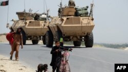 Afghan children pass security forces as they leave a village during an operation against IS militants in Nangarhar Province in May, where the U.S. military denied causing civilian casualties in a recent strike.