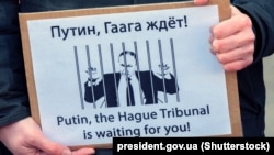 Un afiș cu „Putin, Tribunalul de la Haga te așteaptă”, la un protest din martie 2022, de la Amsterdam împotriva invaziei rusești în Ucraina