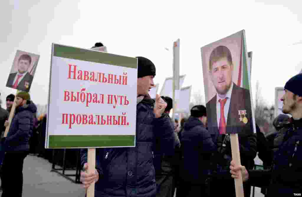 Мітингувальники несуть у руках плакати з гаслами проти російських опозиціонерів...