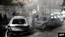 Пожарный обливает автомобиль, который загорелся после минометного обстрела. Дамаск, 26 марта 2013 года.