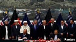 While the chief executive of the Afghan government Abdullah Abdullah (fourth from left) and President Ashraf Ghani (fourth from right) look on, Afghan National security adviser Hanif Atmar (at table,right) and U.S. Ambassador James Cunningham sign a bilateral security agreement in Kabul on September 30.