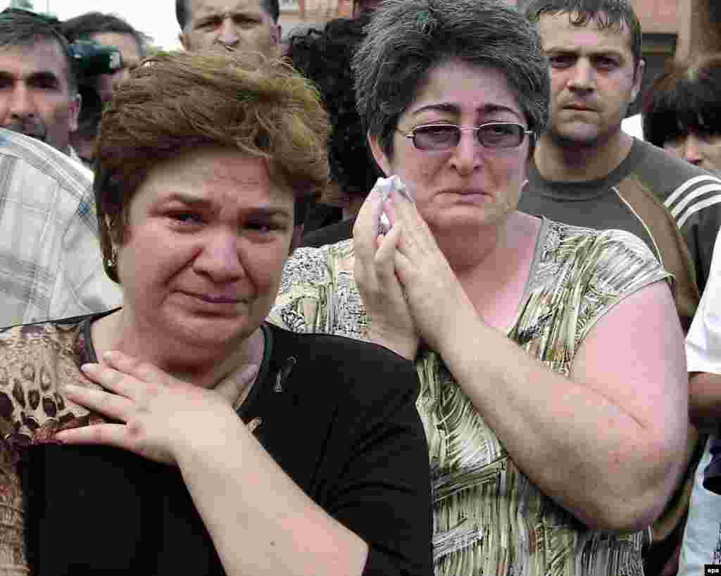 Women stand outside the school on the first day of the hostage crisis.