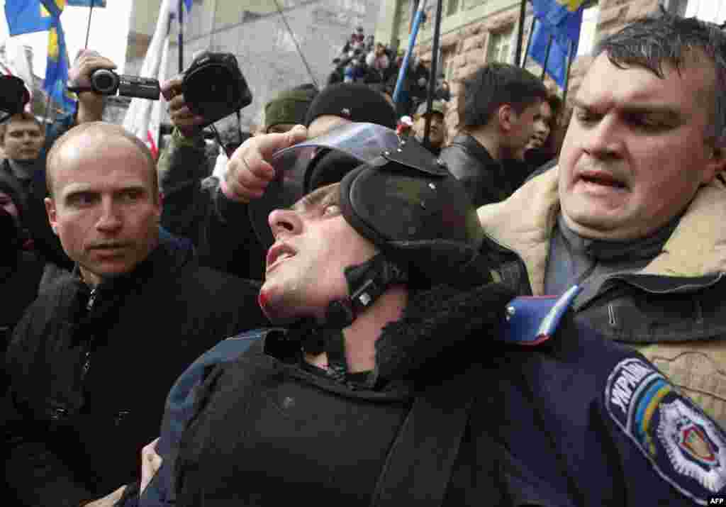 Opposition activists grab the helmet of a riot policeman as they try to enter the building of Kyiv's city council to prevent a session in the Ukrainian capital. (AFP/Anatolii Stepanov)