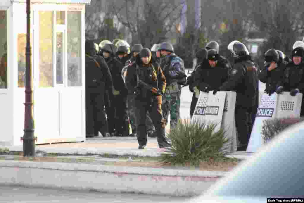 Тегіс оқпанды қару және Калашников автоматын ұстаған полиция қызметкерлері митингіге шыққандарды бақылап тұр. Ақтау, 19 желтоқсан 2011 жыл